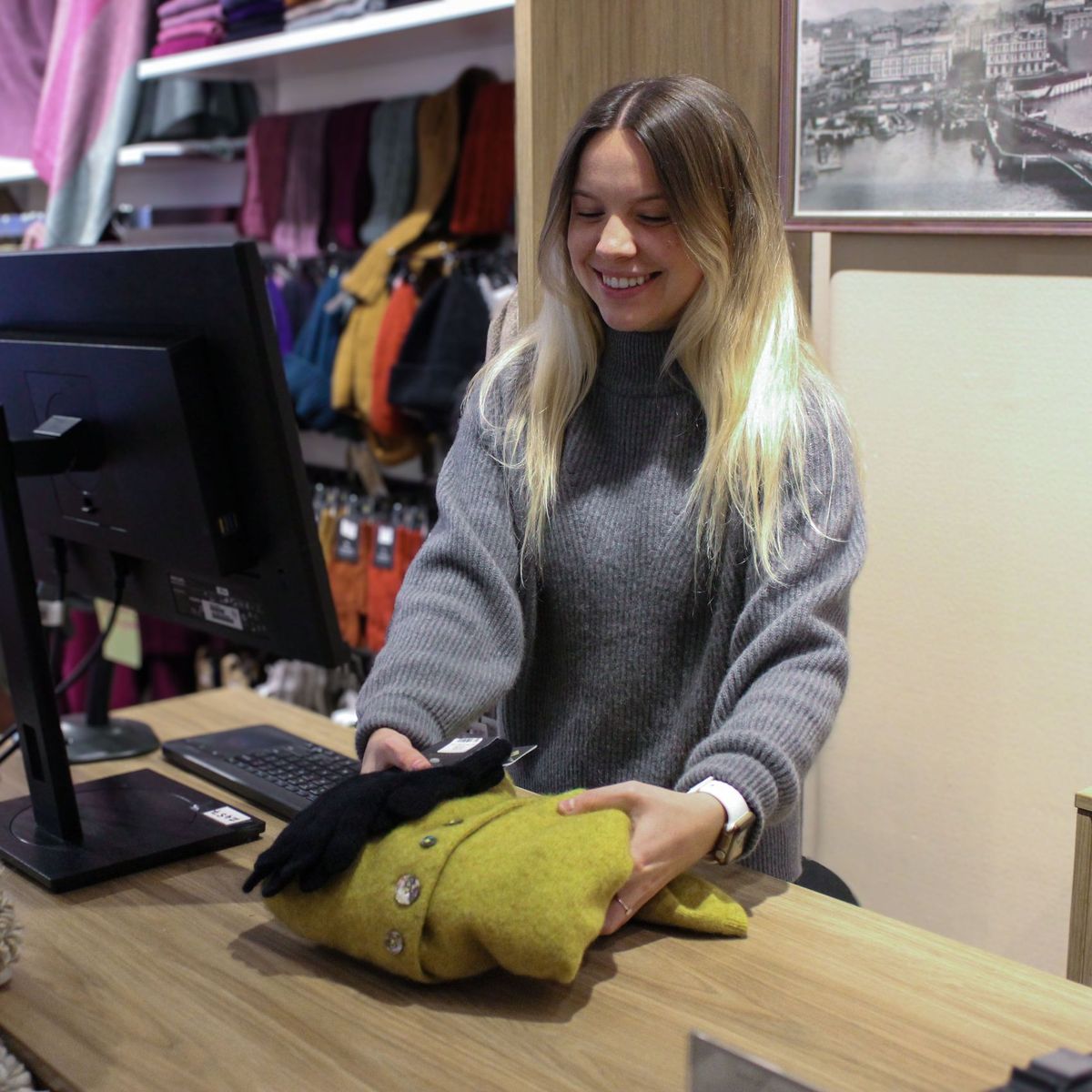 Great Kiwi Yarns team member folding a cardigan at the counter