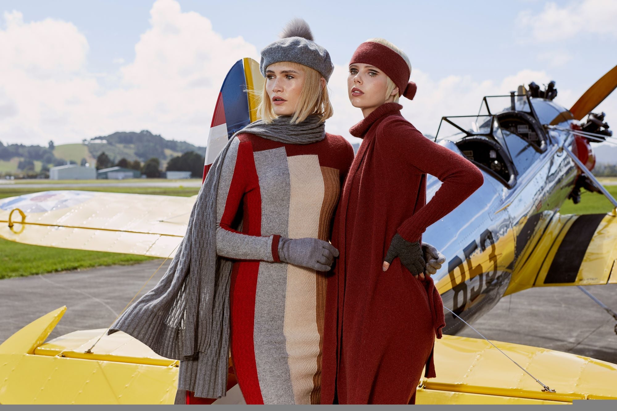 classy ladies wearing slim woolen dresses and beret in front of a plane