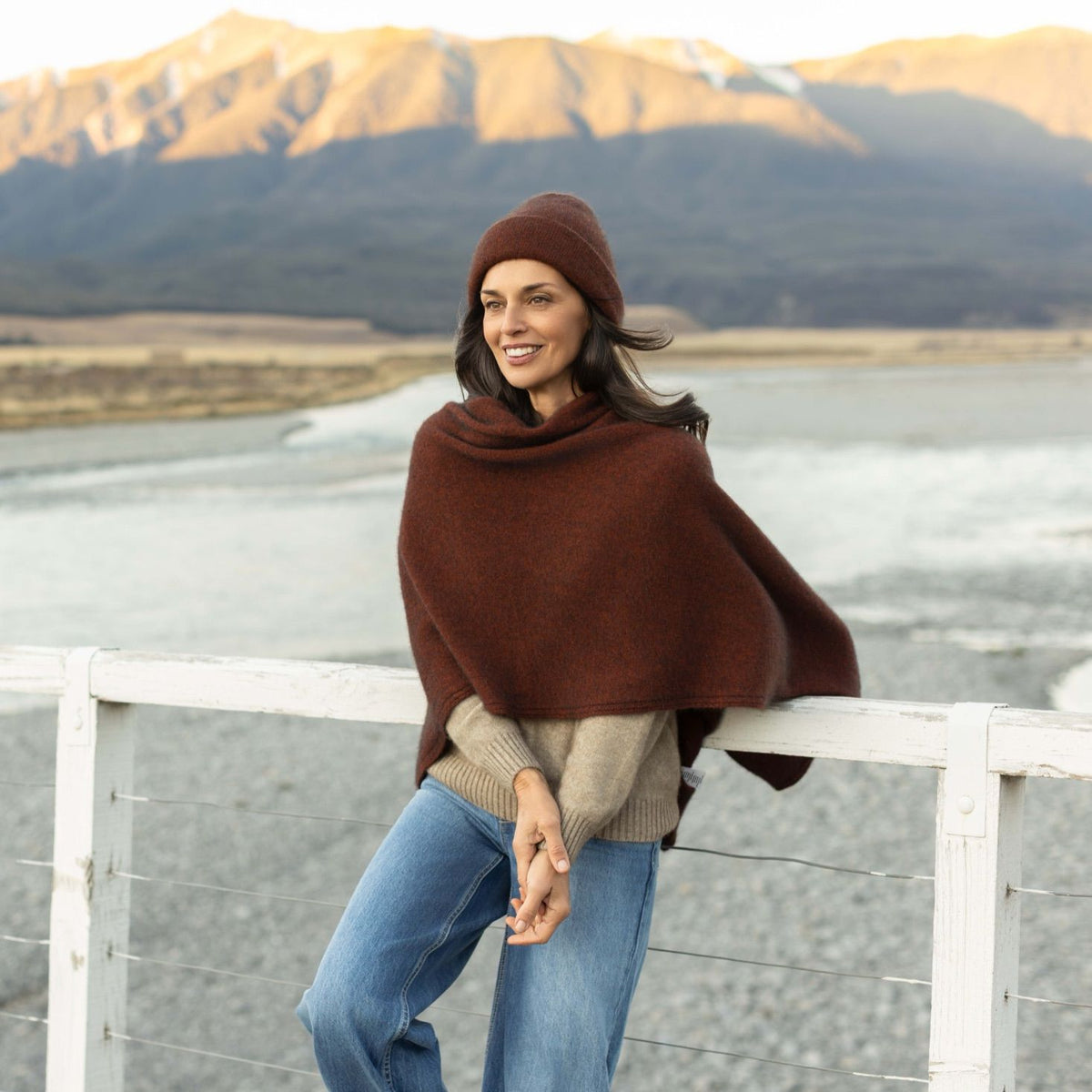 Woman in a rust wool wrap by a New Zealand river